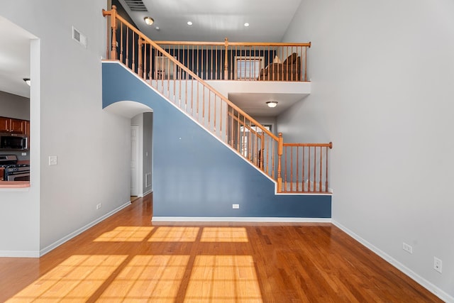 2366 Georgetown Cir, Aurora, IL 60503 - staircase featuring baseboards, a high ceiling, arched walkways, visible vents, and wood finished floors