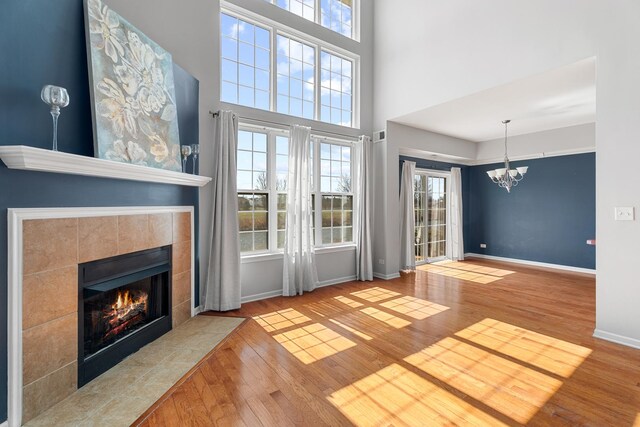 2366 Georgetown Cir, Aurora, IL 60503 - unfurnished living room with a healthy amount of sunlight, a fireplace, wood finished floors, and an inviting chandelier