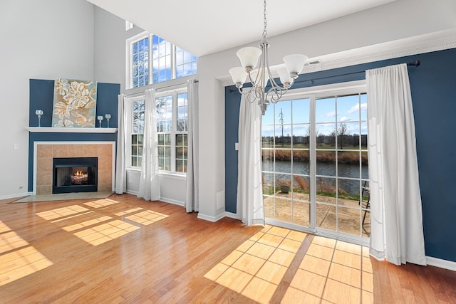 2366 Georgetown Cir, Aurora, IL 60503 - unfurnished dining area with an inviting chandelier, a water view, baseboards, a fireplace, and wood finished floors
