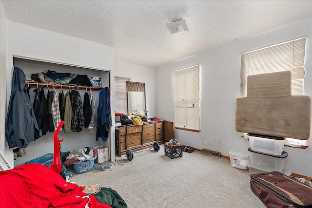 bedroom featuring carpet flooring, baseboards, a textured ceiling, visible vents, and a closet