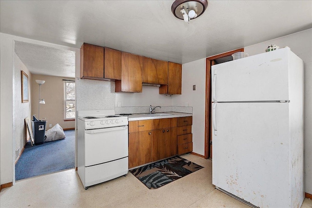 kitchen featuring light countertops, white appliances, a textured ceiling, a sink, and brown cabinets