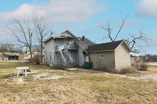 rear view of house featuring stairway, a yard, and concrete block siding