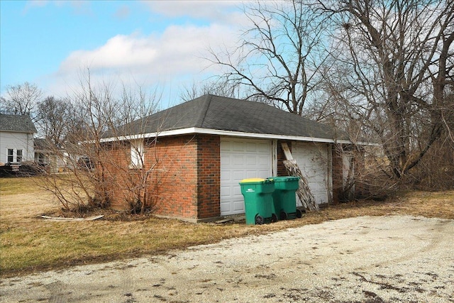 view of side of property with an attached garage, brick siding, and roof with shingles