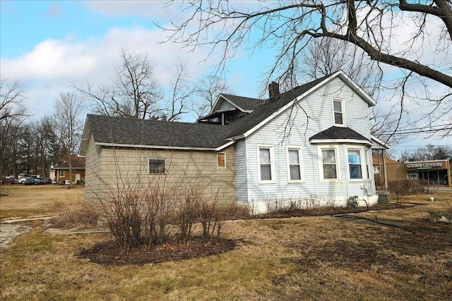 view of home's exterior featuring a chimney, a shingled roof, and a yard