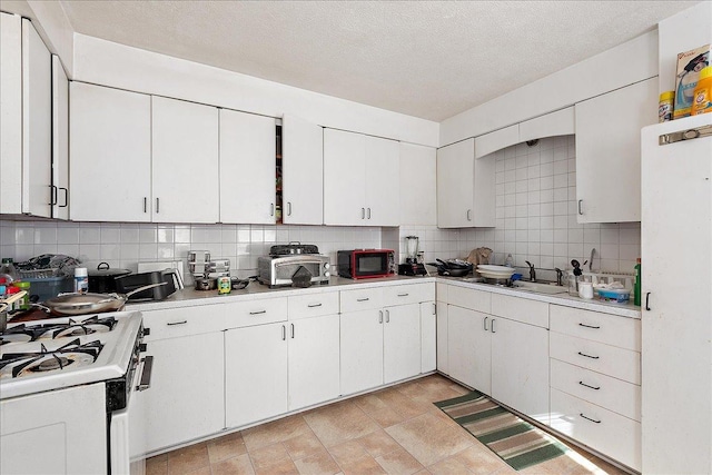 kitchen featuring backsplash, light countertops, and white range with gas stovetop