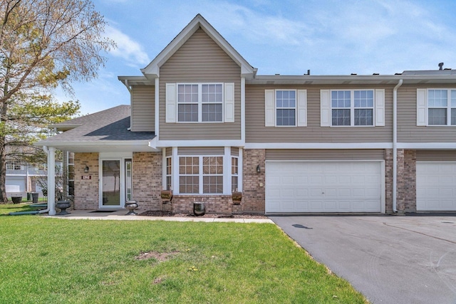 view of front of home featuring brick siding, a garage, a front lawn, and aphalt driveway