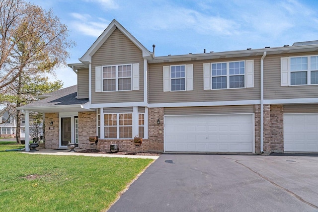 view of front of house with aphalt driveway, brick siding, a front yard, and a garage