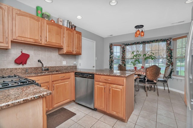 kitchen featuring a peninsula, stainless steel dishwasher, a sink, light stone countertops, and light tile patterned floors