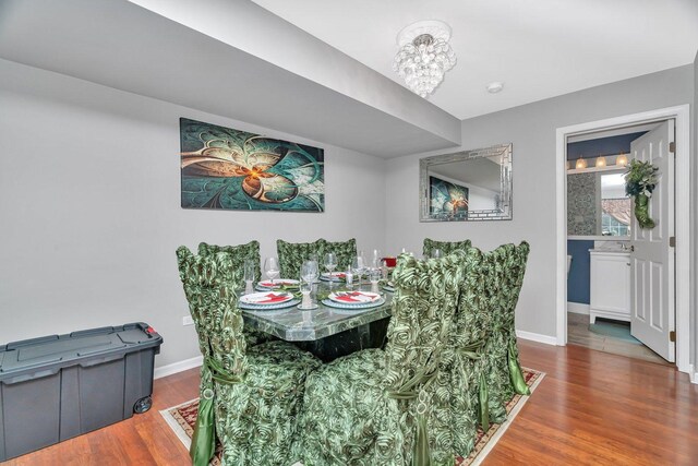 dining space with baseboards, a notable chandelier, and wood finished floors