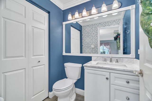 bathroom with toilet, crown molding, vanity, and baseboards
