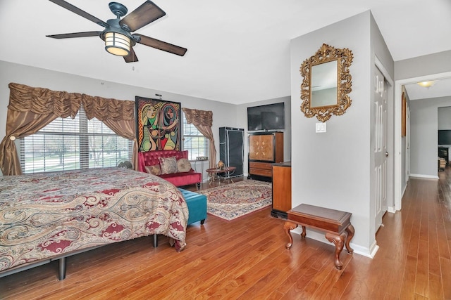 bedroom with ceiling fan, baseboards, and wood finished floors