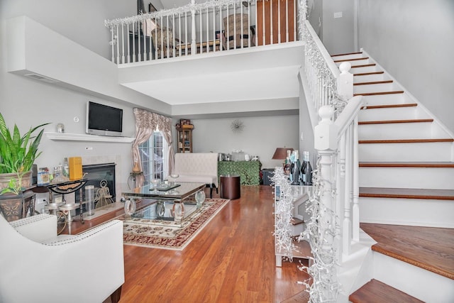 living area featuring a tile fireplace, a high ceiling, wood finished floors, and stairs