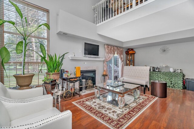 living room with a towering ceiling, wood finished floors, and a fireplace