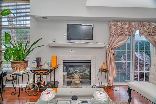 living room with a tile fireplace, wood finished floors, and visible vents