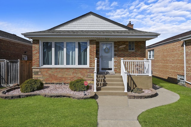 bungalow-style home with a front lawn, fence, a porch, and brick siding