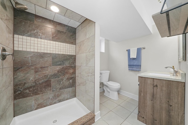 full bathroom with baseboards, toilet, vanity, tiled shower, and tile patterned flooring