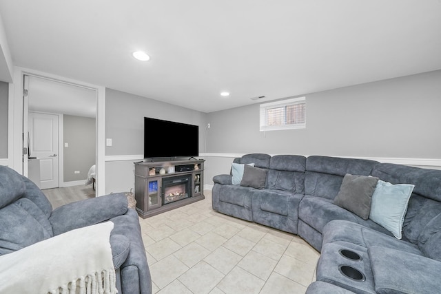 living room featuring light tile patterned floors, recessed lighting, a glass covered fireplace, and visible vents