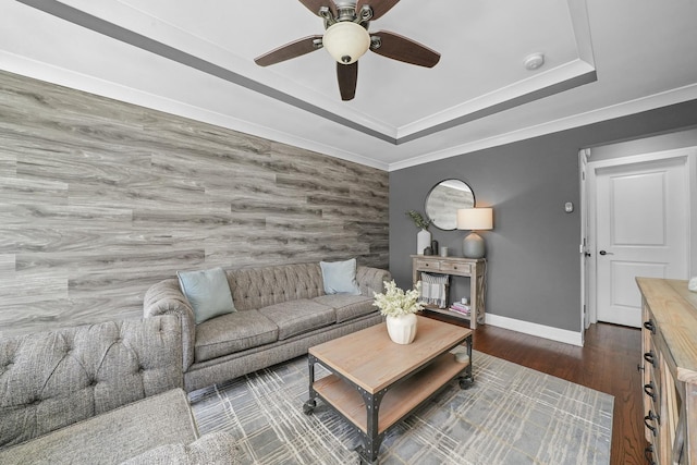 living area featuring crown molding, baseboards, wood finished floors, a ceiling fan, and a raised ceiling