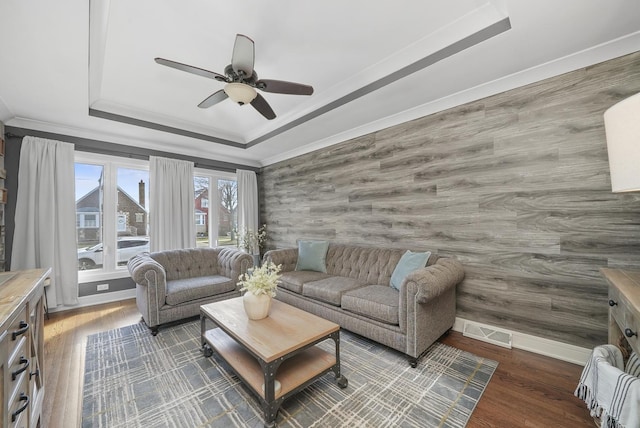living area featuring visible vents, baseboards, wood finished floors, a ceiling fan, and a raised ceiling
