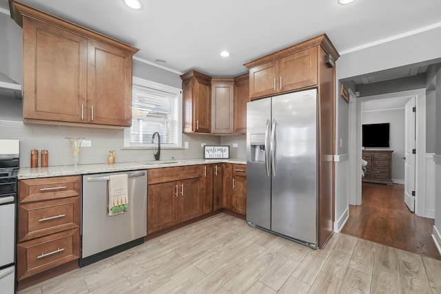 kitchen featuring light wood-type flooring, brown cabinetry, appliances with stainless steel finishes, and tasteful backsplash