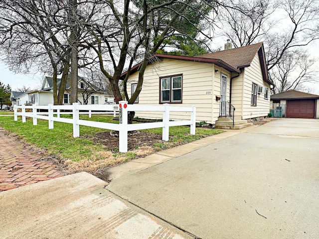 view of home's exterior featuring an outdoor structure, concrete driveway, a fenced front yard, a garage, and a chimney