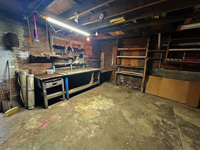 unfinished basement featuring a workshop area and brick wall