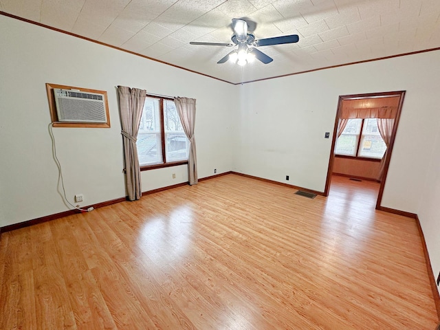 empty room featuring crown molding, light wood finished floors, a wall mounted air conditioner, baseboards, and visible vents