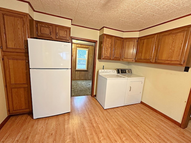 washroom with washing machine and dryer, light wood finished floors, baseboards, cabinet space, and ornamental molding
