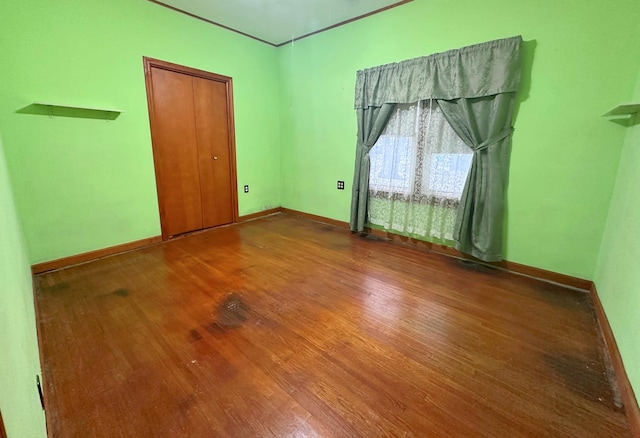 spare room with baseboards and wood finished floors