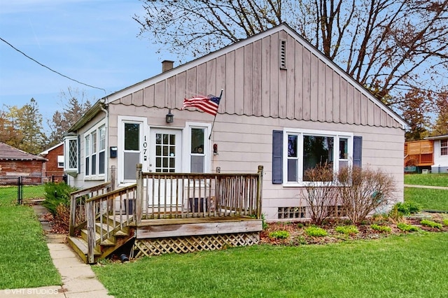 rear view of property featuring a deck, fence, a chimney, and a lawn