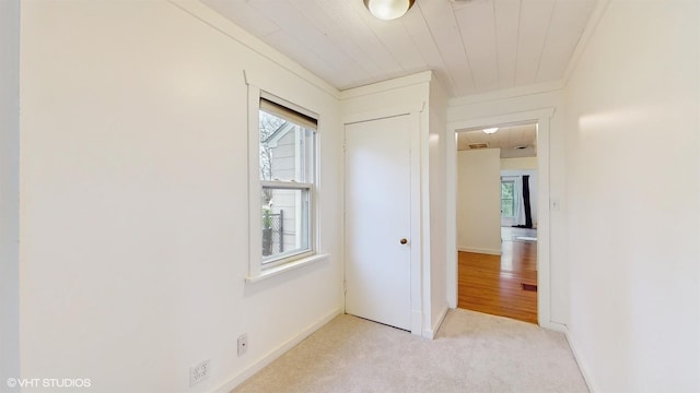 unfurnished bedroom with light colored carpet, crown molding, baseboards, and a closet