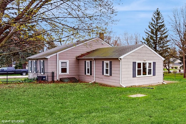 back of house with a lawn, fence, roof with shingles, and a chimney