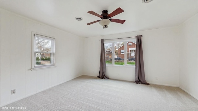 carpeted spare room featuring visible vents, ceiling fan, baseboards, and plenty of natural light