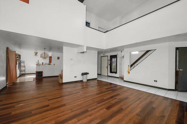 3917 Sunset Ave, Markham, IL 60428 - unfurnished living room featuring a towering ceiling, a notable chandelier, baseboards, and wood finished floors