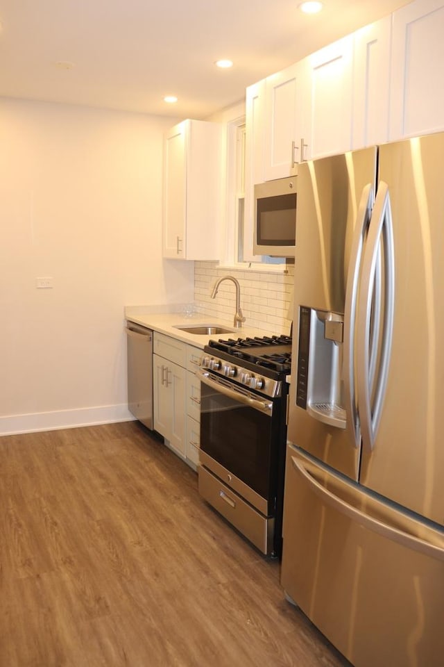 3418 N Nordica Ave, Chicago, IL 60634 - kitchen featuring white cabinetry, decorative backsplash, a sink, appliances with stainless steel finishes, and wood finished floors