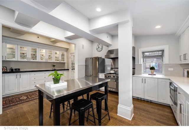 kitchen featuring stainless steel appliances, decorative backsplash, wall chimney range hood, and white cabinets
