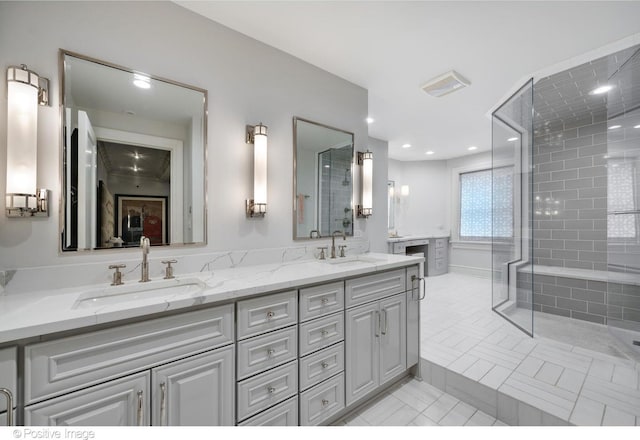 bathroom featuring a tile shower, tile patterned flooring, double vanity, and a sink