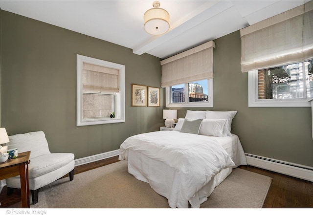 bedroom with baseboards, beamed ceiling, baseboard heating, and wood finished floors