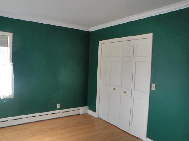810 13th Ave, Mendota, IL 61342 - unfurnished bedroom featuring a baseboard heating unit, wood finished floors, crown molding, and a closet