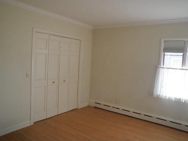 810 13th Ave, Mendota, IL 61342 - unfurnished bedroom featuring a baseboard radiator, wood finished floors, crown molding, and a closet