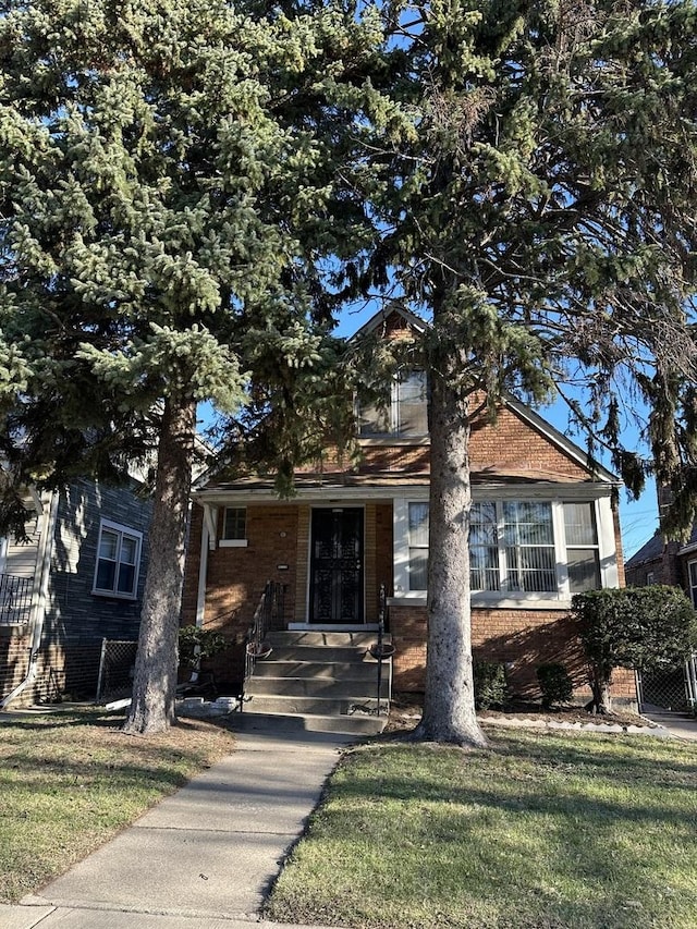 view of front facade with brick siding and a front yard