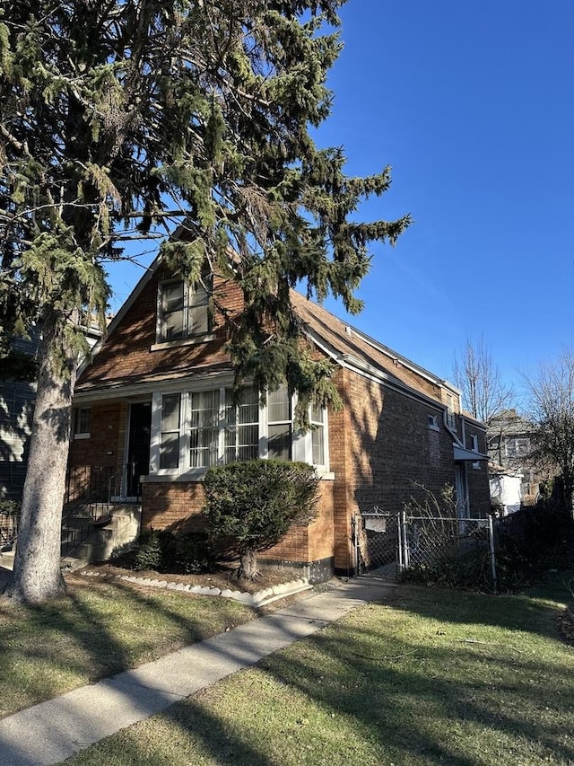 view of side of property featuring a gate, fence, brick siding, and a yard
