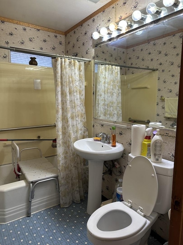 bathroom with a sink, wallpapered walls, and toilet