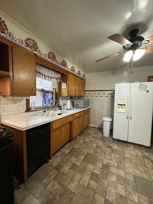 kitchen featuring light countertops, stone finish flooring, brown cabinets, a sink, and black appliances