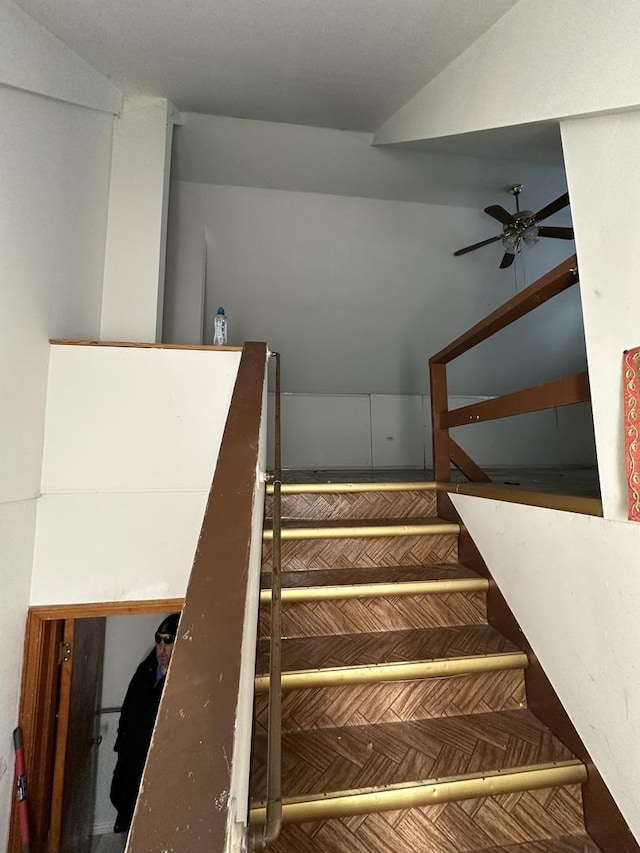 staircase with vaulted ceiling and a ceiling fan
