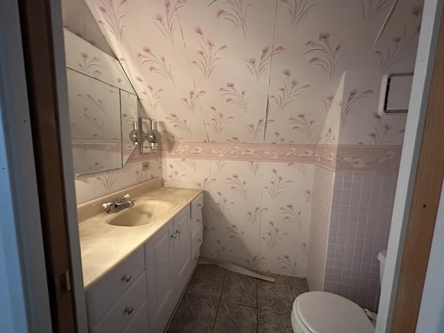 half bath featuring wallpapered walls, vanity, and toilet