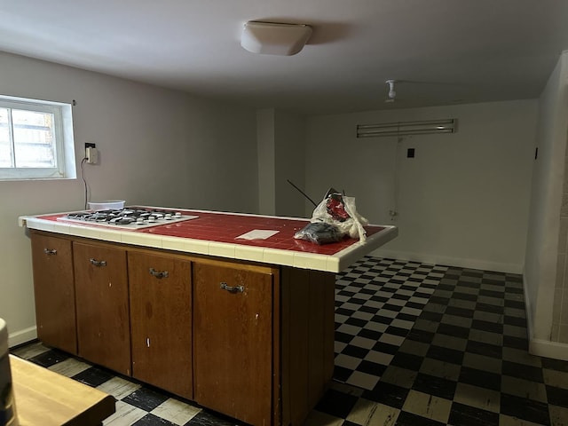 kitchen with white gas stovetop, tile countertops, baseboards, and light floors