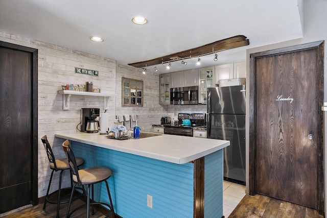 16 Oak Glen Dr, Galena, IL 61036 - kitchen with light countertops, a peninsula, appliances with stainless steel finishes, glass insert cabinets, and a breakfast bar area
