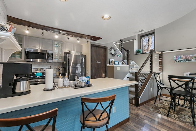 16 Oak Glen Dr, Galena, IL 61036 - kitchen featuring a breakfast bar area, tasteful backsplash, appliances with stainless steel finishes, glass insert cabinets, and dark wood-type flooring