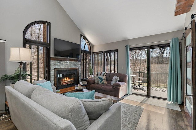 16 Oak Glen Dr, Galena, IL 61036 - living area with a stone fireplace, high vaulted ceiling, a barn door, and wood finished floors